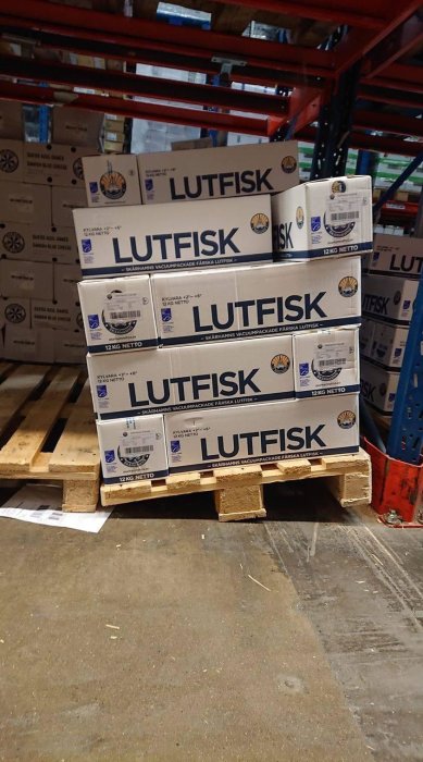 Staplar med förpackningar av lutefisk på en pall i ett lager.