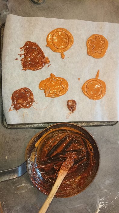 Ojämna hemmagjorda chokladkakor på bakplåtspapper bredvid en skål med smet och en slickepott.