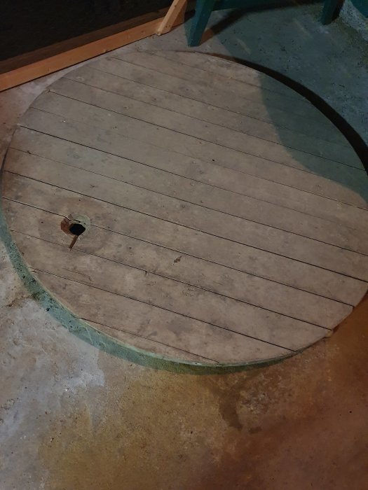 En oanvänd vattenbrunn i källaren täckt med en rund trälock.