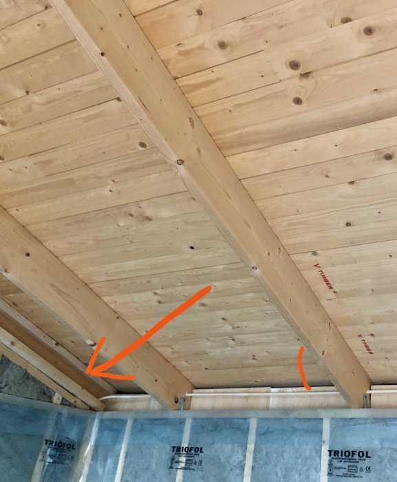 Bild av träkonstruktion i tak med pil som pekar på en träregel där masonit fästs.