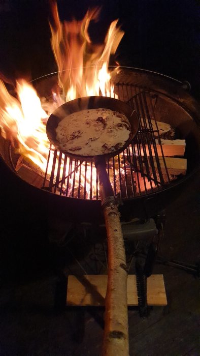 Pannkaka med fläsk steks över öppen eld i mörkret.