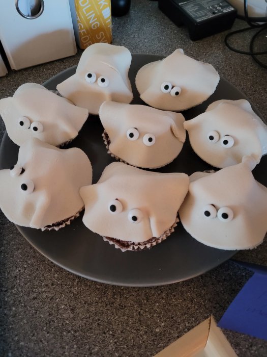 Bakverk formade som spöken med vita glasyrer och ögon på en tallrik.