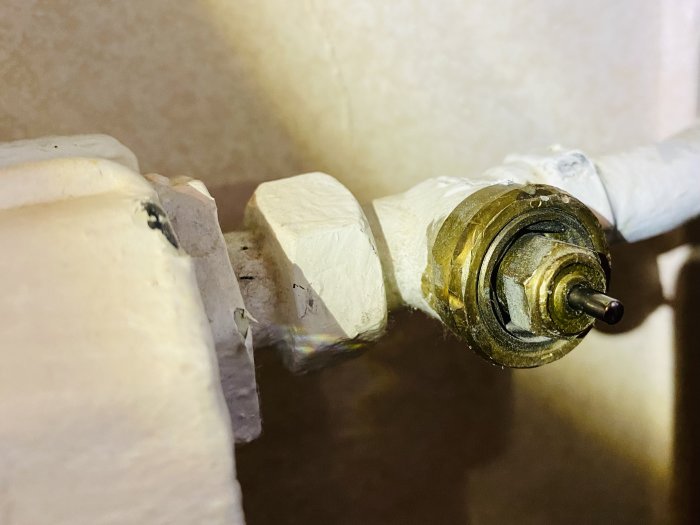Öppen äldre Danfoss-radiatorventil utan termostatvred, med synligt stift och packbox och några vattendroppar.