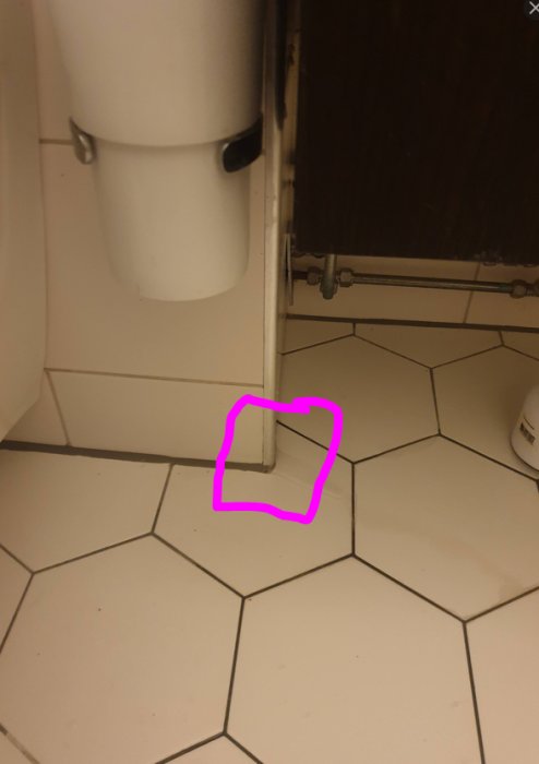 Badrumsgolv med markerad plats där inget vatten bör rinna intill en toalettpappershållare.