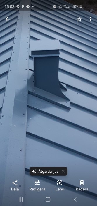 En nyinstallerad takkupa på ett plåttak med metallbeslag och skruvar synligt.