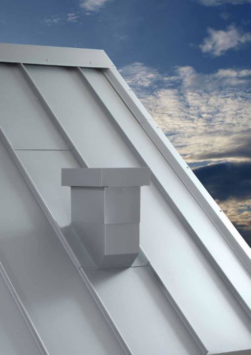 Prefabricerad ventilationshuv monterad mitt på en takås av metall, mot en bakgrund av himmel med moln.