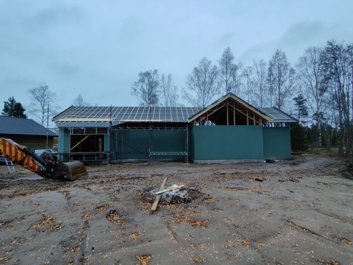 Hus under konstruktion med inklädd takfot och synliga träreglar av tak och väggar, delvis molnig himmel.