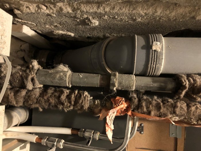 Vattenledningar med isolering som kan innehålla asbest i ett äldre hus under renovering.