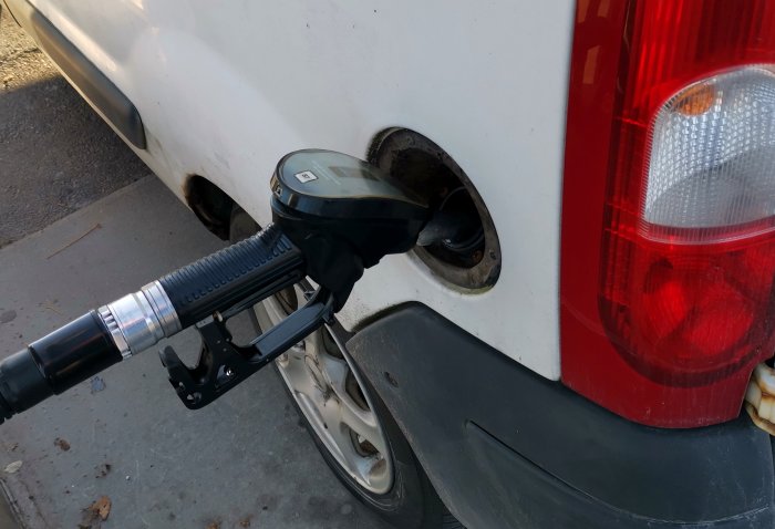 En bensinpump i ett fordonstanklock med texten som antyder att bilen tankas full.