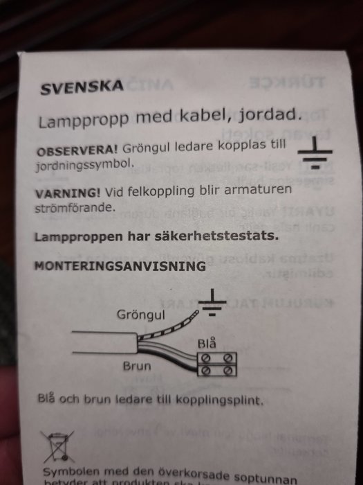 Instruktionsblad som visar hur man kopplar jorden till en lampa med gröngul, blå och brun ledare.