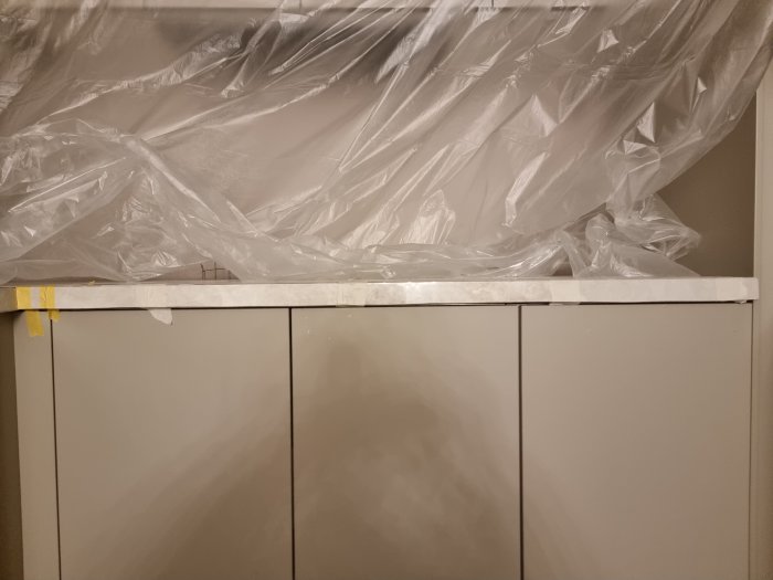 Köksrenovering med snett kapad granitkeramikplatta på bänkskivans framsida, skyddad av plast.