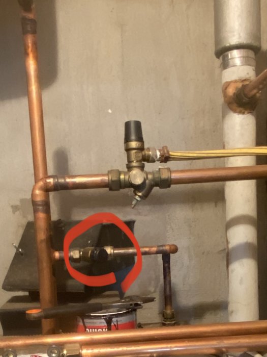 Rörinstallation med fokus på en specifik skruv omringad av en röd cirkel.