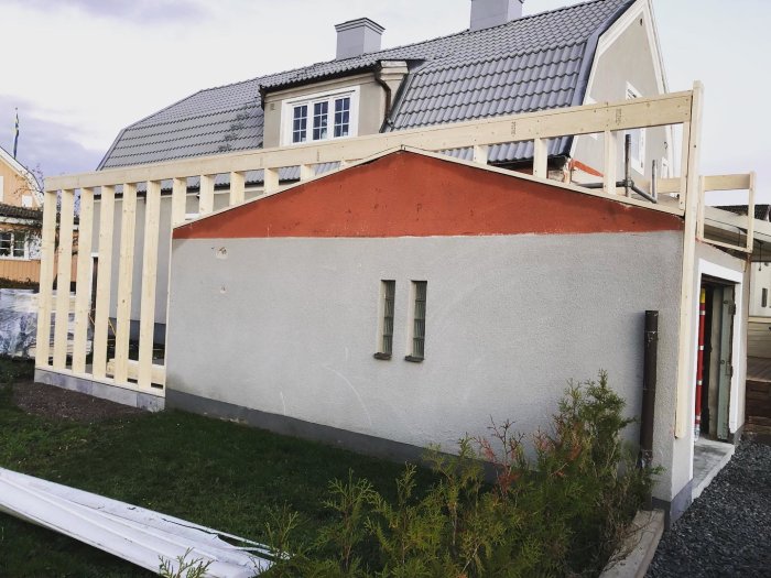 Garage under ombyggnad till gäststuga med nya reglar uppsatta mot gammal stenstruktur.