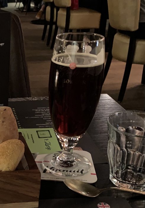 Ett glas Grolsch Premium Herfstbok öl på en restaurangbord med bröd och en meny.