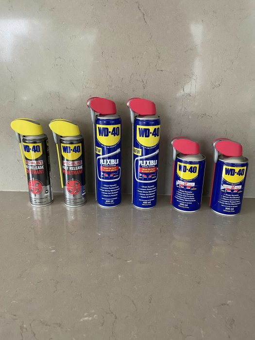 Flera burkar med WD-40 smörjmedel på en stenbänk som underhåll för verktyg.