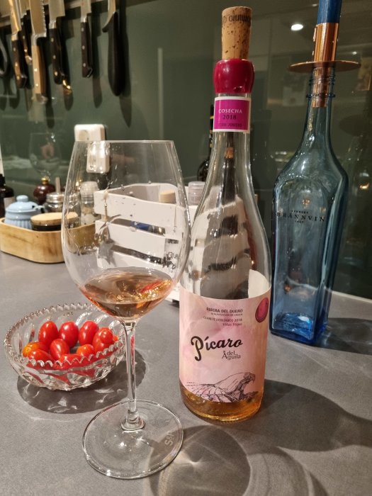 En flaska rosévin från Ribera del Duero bredvid ett glas med vin och skål med körsbärstomater.