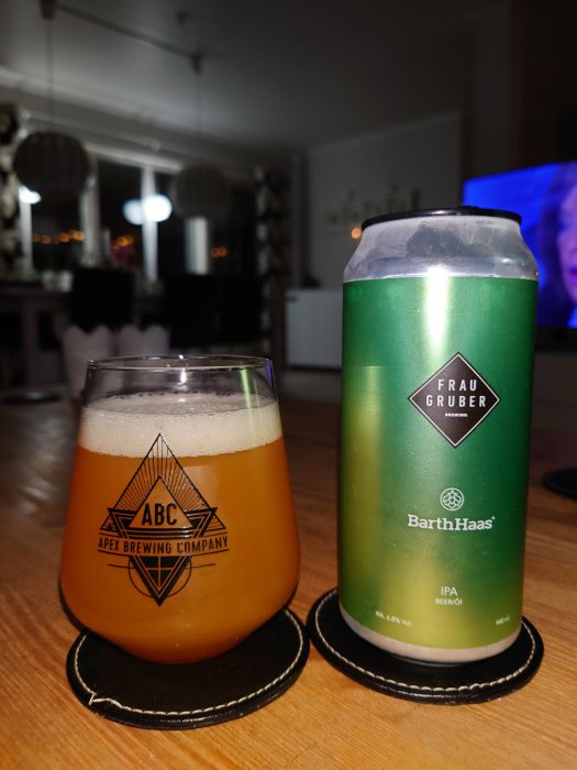 Ölglas märkt "ABC" och burk av "Frau Gruber Brewing" på bord, inne i ett vardagsrum.