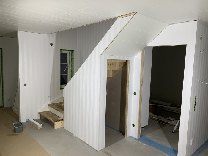 Renoveringsarbete i ett trapphus med vita väggar och nytt innertak, installation av spottar synlig.