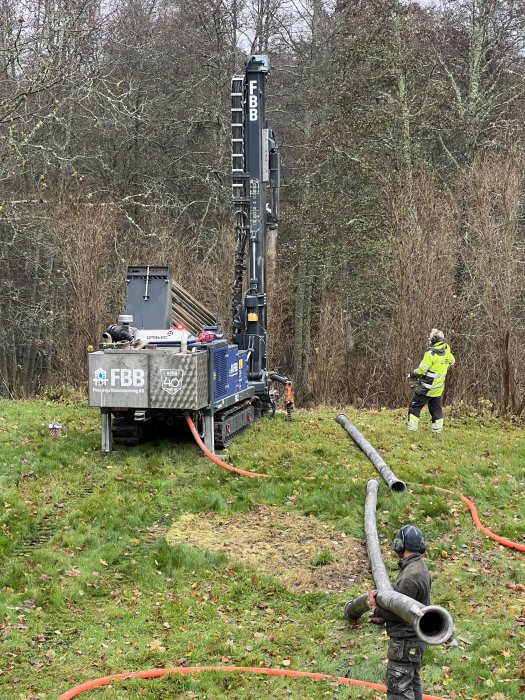 Borrningsrigg på fält med arbetare som förbereder utrustning för bergvärmehål.