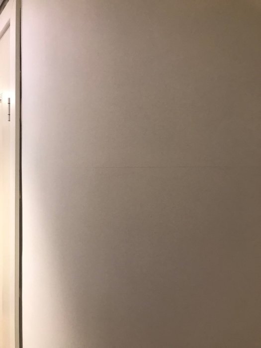 Spricka i nygrundmålad vägg där två gipsskivor möts efter borttagning av vävtapet.