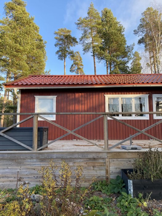 Rödfärgat sommarhus med nyinstallerat plåttak och en ovanligt hög takfot kontra takets lutning.