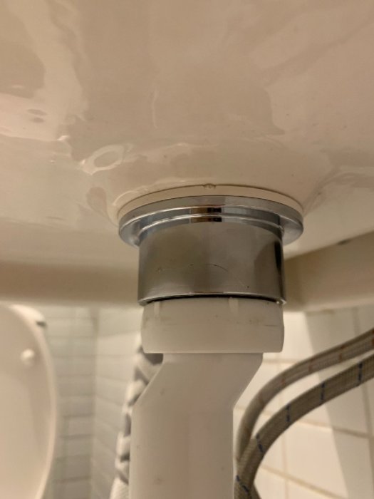 Närbild av en fastmonterad bottenventil under handfat utan synlig skruv eller fäste.