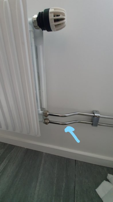 Radiator med termostat och rör, pil visar var det blir varmt först.