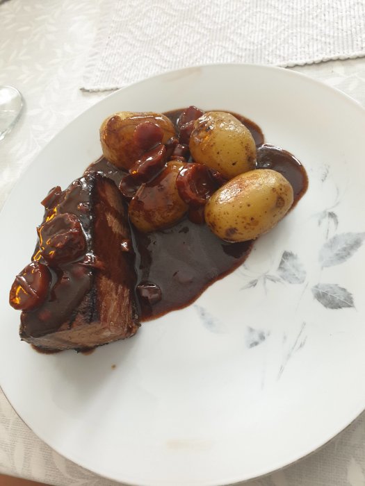En tallrik med långbakad högrev och potatis täckta av rödvinssås.