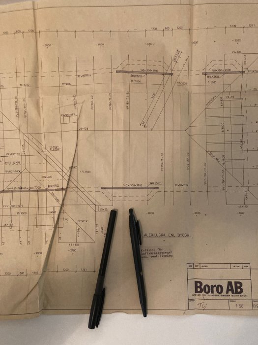 Ritning av takstolar på papper med två pennor som markerar takstolarna 4 och 5, logotypen för Boro AB i hörnet.