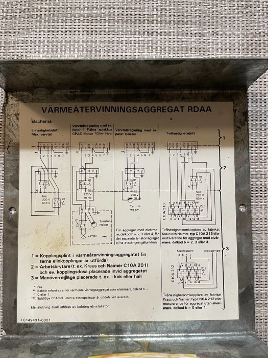 Elschema på ett värmeteråtervinningsaggregat med kopplingar och inställningar mot en målad vägg och en flätad yta.