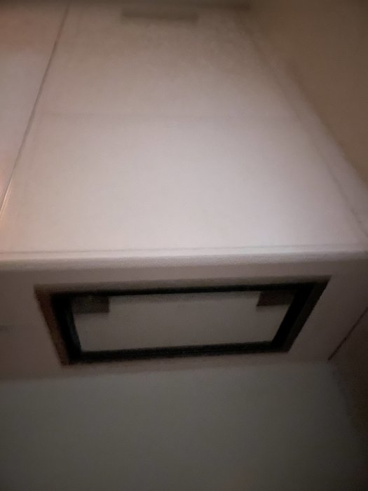 Osymmetriskt fotograferad bild av en vit kökslåda med ett handtag, öppenvinkel och bakgrund är suddig.