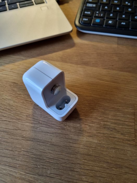 Apple USB-laddare utan stickkontakt, redo för kabelanslutning, på ett skrivbord.