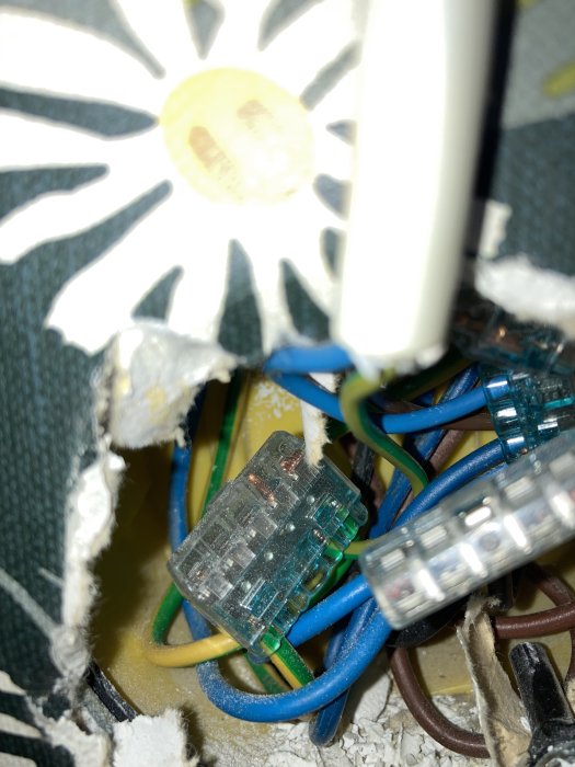 Ett trångt utrymme med synliga elektriska ledningar och kopplingar, där en utanpåliggande kabel leder till tvättmaskinsuttaget.