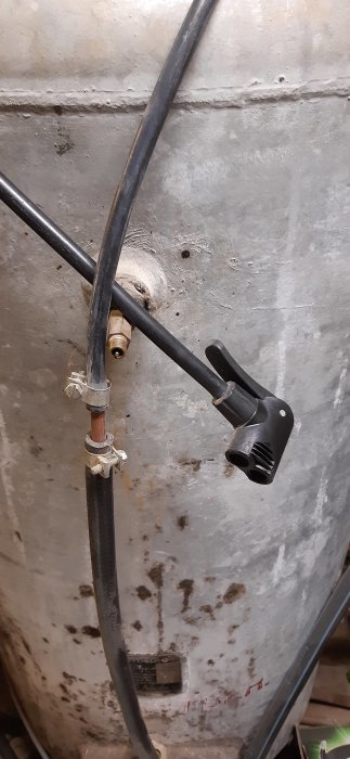 Hydrofortank med schraderventil och slang från däckpump, kopplad till kylskåpskompressor.