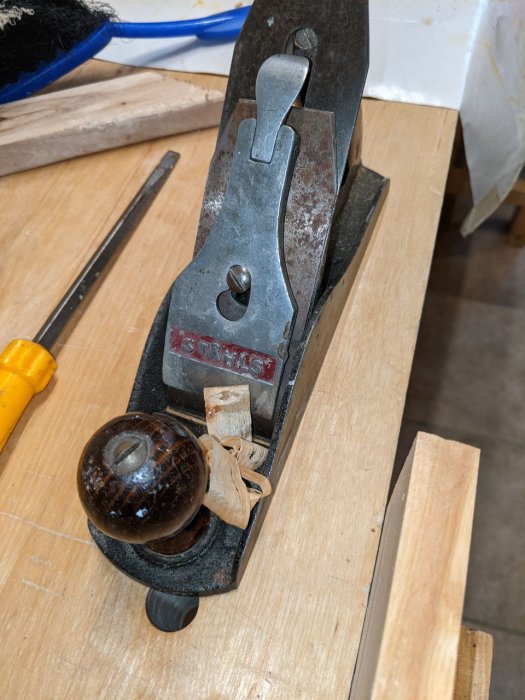 Gammal Ståhls hyvel på träplanka med skavanker och synlig användning, del av byggprojekt.