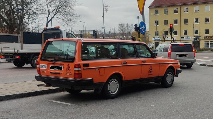 Orange Volvo 240 GL i klassisk Televerket-design parkerad på gata.