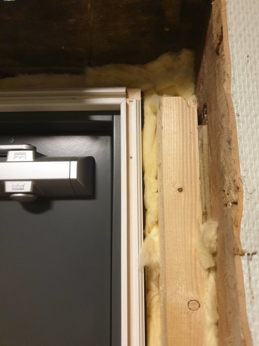 Montering av notspårslist vid en hallfönstersida, med synlig isolering och en dörranslutning.