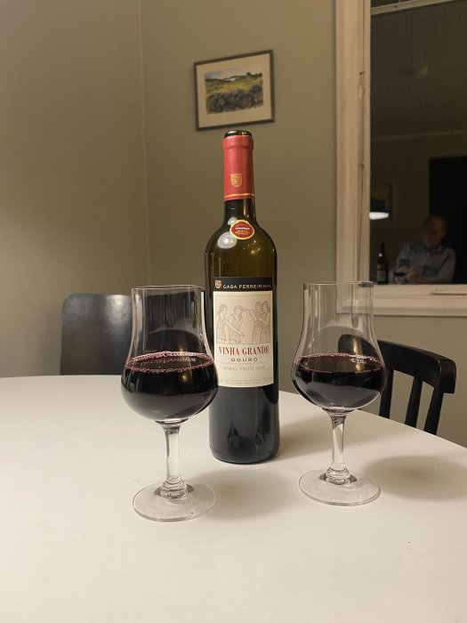 Flaska och två glas med rött vin på bord, portugisiskt vin från Douro med toner av mörka bär.