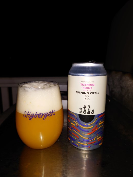 Ölglas med skum och ölburk med texten "Turning Point" på mörk bakgrund.