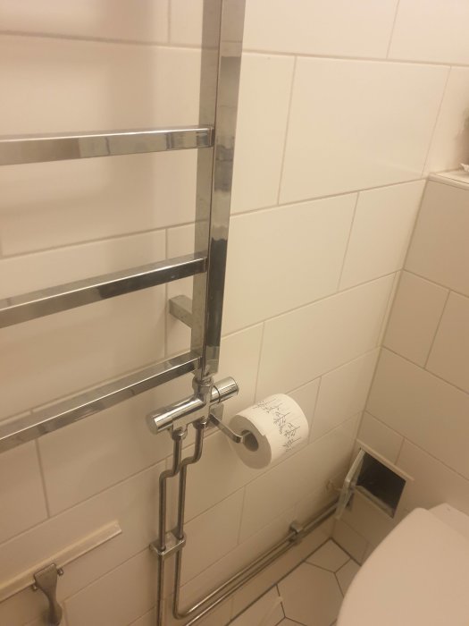 Handdukstork i badrum med vridbara ventiler och en öppnad inspektionslucka i väggen.