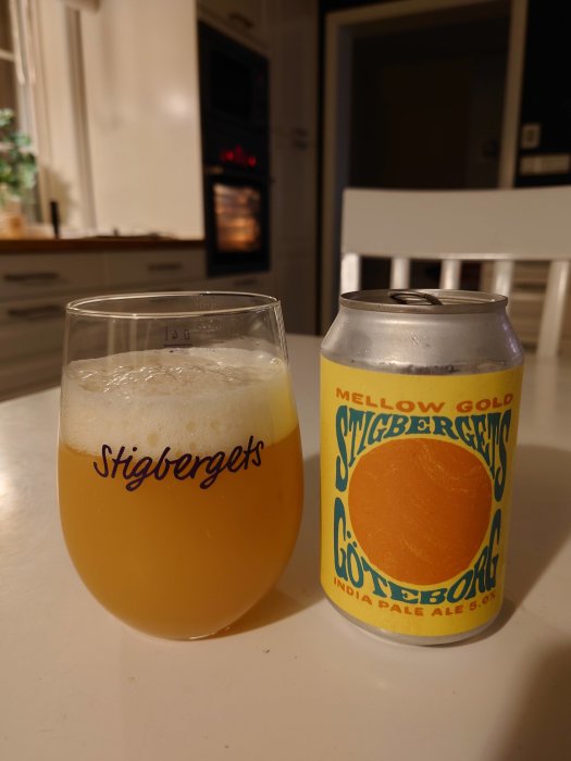 Ett glas och en burk Stigbergets öl på ett bord med en ugn i bakgrunden.