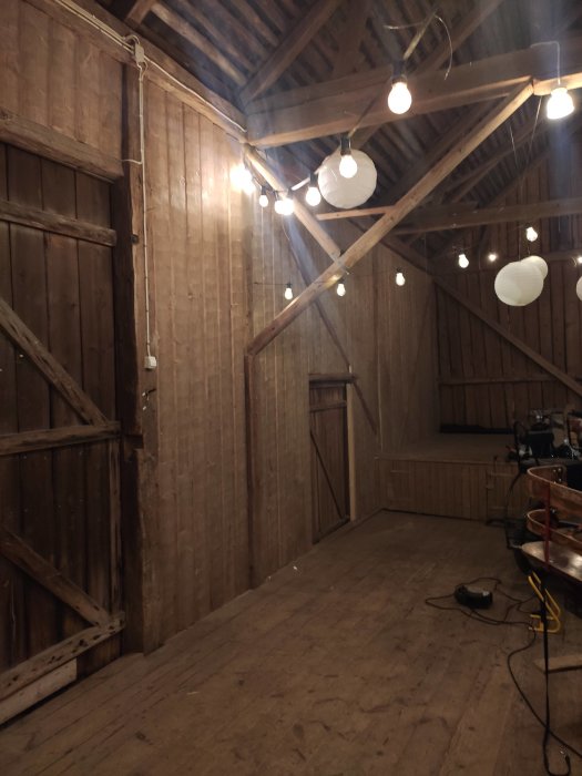 Innertak i loge med isolering och ny timmerpanel, exponerade träbjälkar och hängande lampor.
