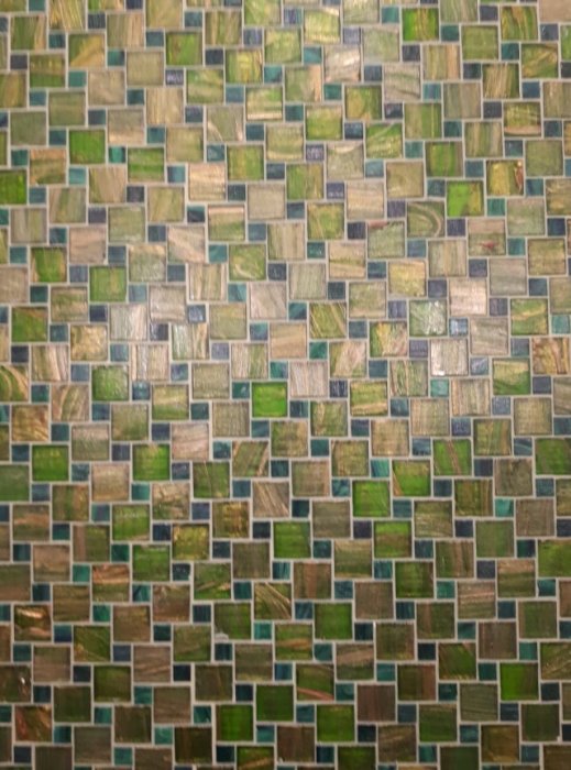 Mosaikkakel i gröna och beige nyanser, cirka 2x2 cm varje, monterade i moduler.