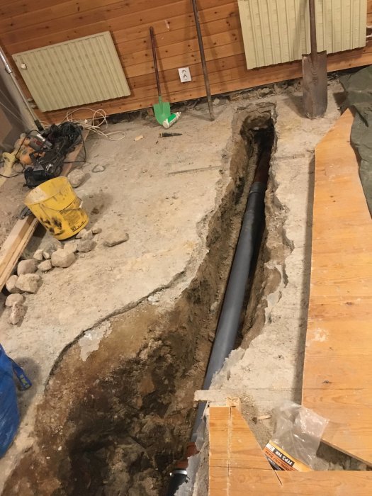 Renoveringsarbete med uppgrävd golvkanal och nyinstallerat avloppsrör i källare.