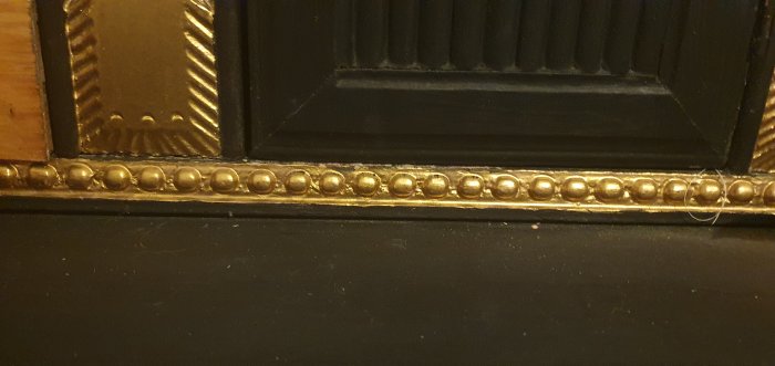 Närbild på farmors antika skrivbord med bladguldsdekor och pärlstavlistsdekoration.