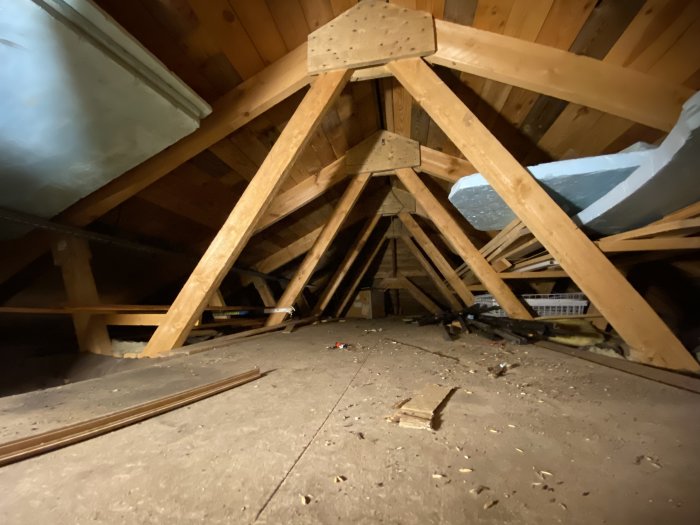 Träkonstruktion och takstolar i ett ouppvärmt garageförråd under takrenovering.