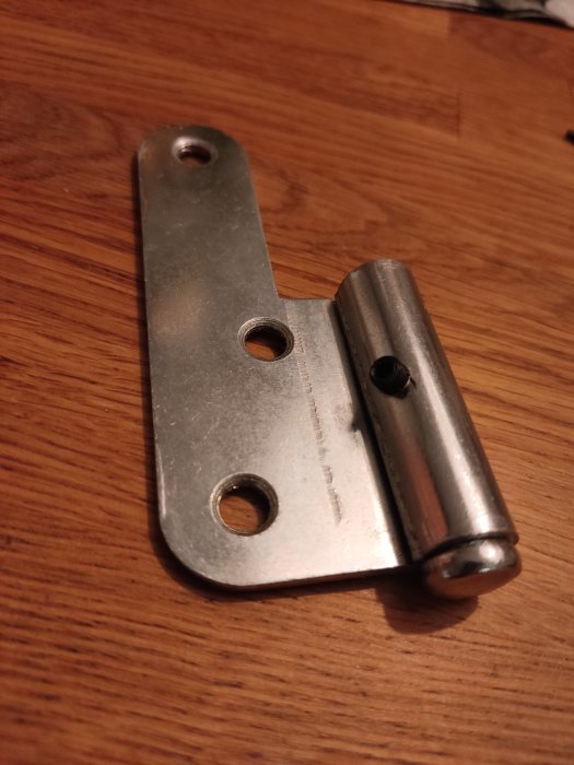 Metallgångjärn från Millers Beslag på träyta med justeringsskruv synlig.