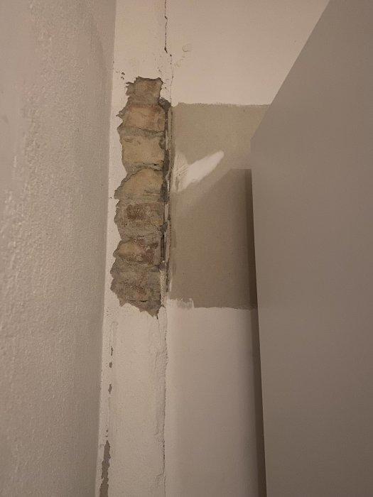 Glipa mellan skåp och bakvägg där puts tagits bort som avslöjar del av murstock.