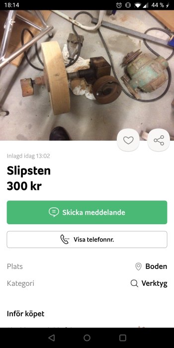 Gammal slipsten med motor och diverse verktyg på betonggolv.