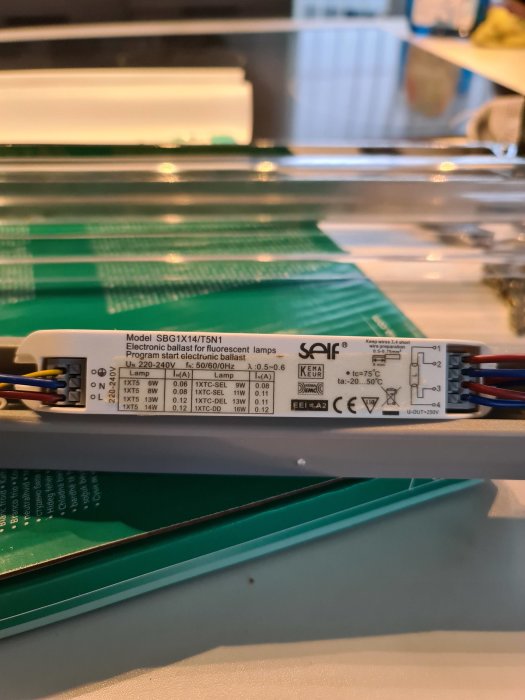 Elektroniskt driftdon för lysrör med modellnummer och tekniska specifikationer på en etikett.